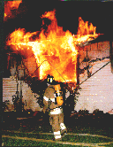 Firefighters outside a structure engulfed in flames