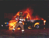 A firefighter prepares to attack a pick-up truck on fire