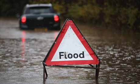 A sign reads "Flood" in a street filled with water